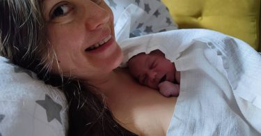 Matka po pôrode s nahým bábätkom na hrudi. Matka sa usmieva a hľadí do objektívu.