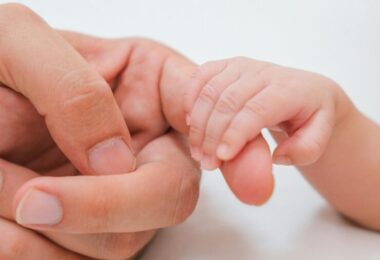 Ruka novorodenca sa dotýka ruky matky