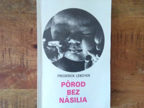 Kniha Pôrod bez násilia položená na drevenom podklade. Na obálke je záber na tvár bábätka.