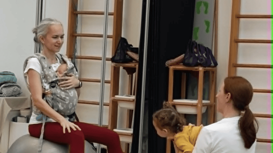 Ľudka Macejová na stretnutí žien v Prešove. Sedí na fitlopte a v nosiči má bábätko.